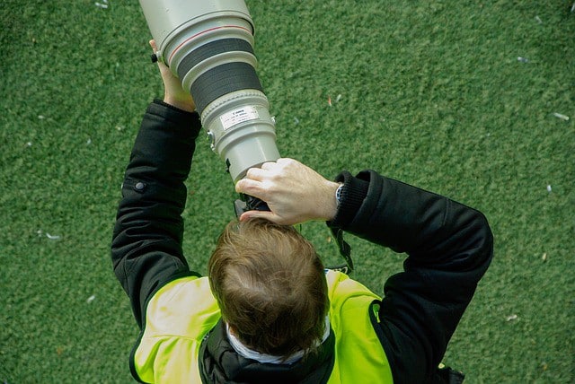 Photographe de presse utilisant un téléobjectif pour prendre des photos sur le terrain lors d’un événement.