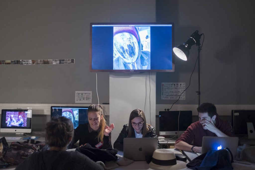 étudiants en salle de retouche rigolent en regardant leur ordinateur