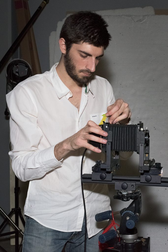 Un étudiant de l'ETPA en chemise blanche manipule du matériel photo à l'école.