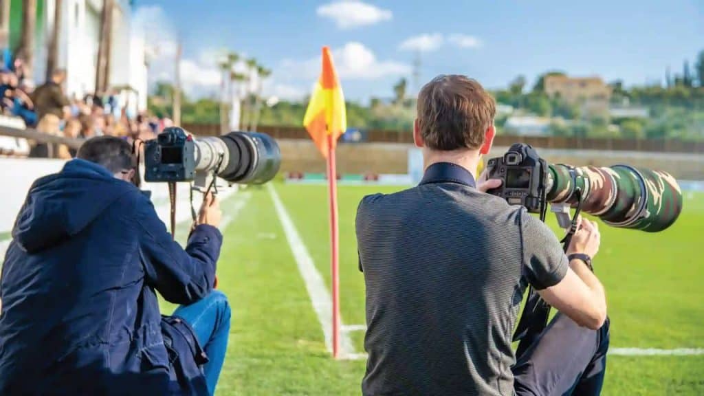 Photographe de sports en action lors d’un événement sportif, appareil photo équipé d’un téléobjectif.