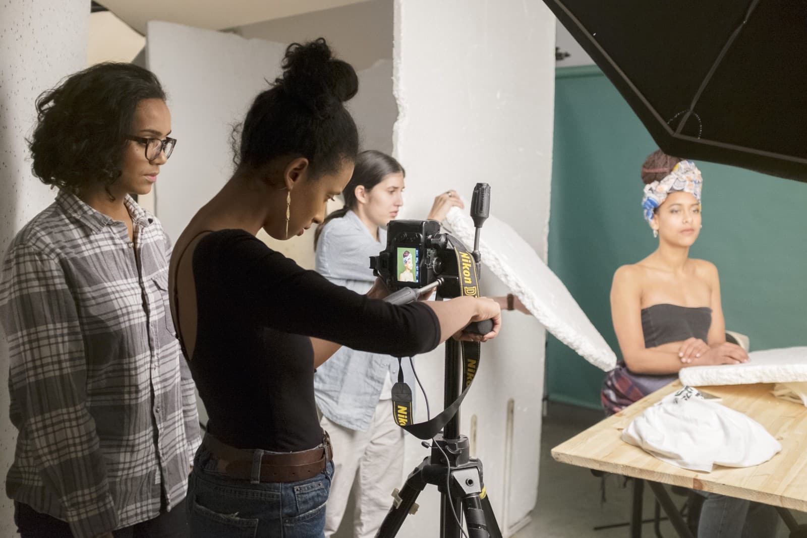 Elève photographe entouré de collaborateurs travaillant sur les éclairages et les réglages.