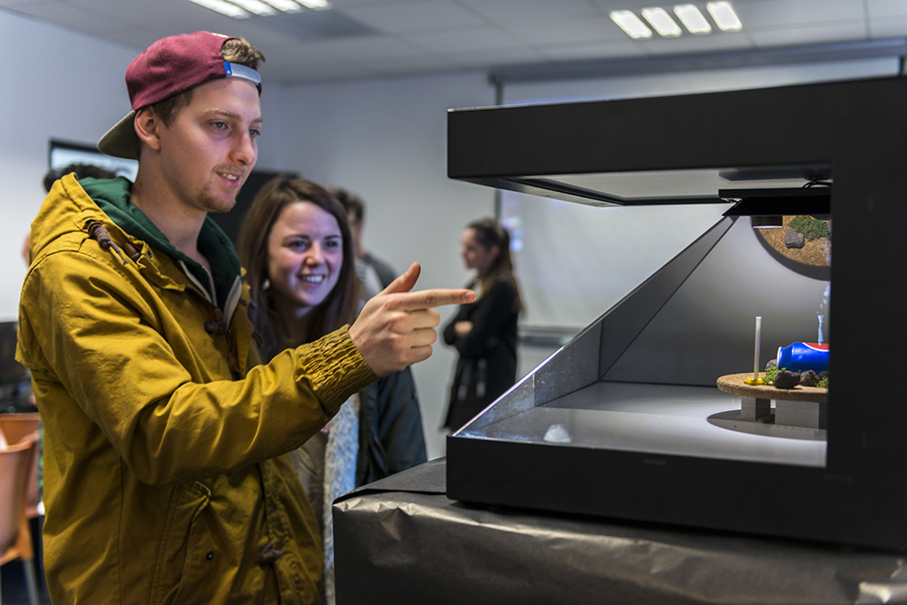 Un étudiant avec une casquette rouge montre une composition photo. 