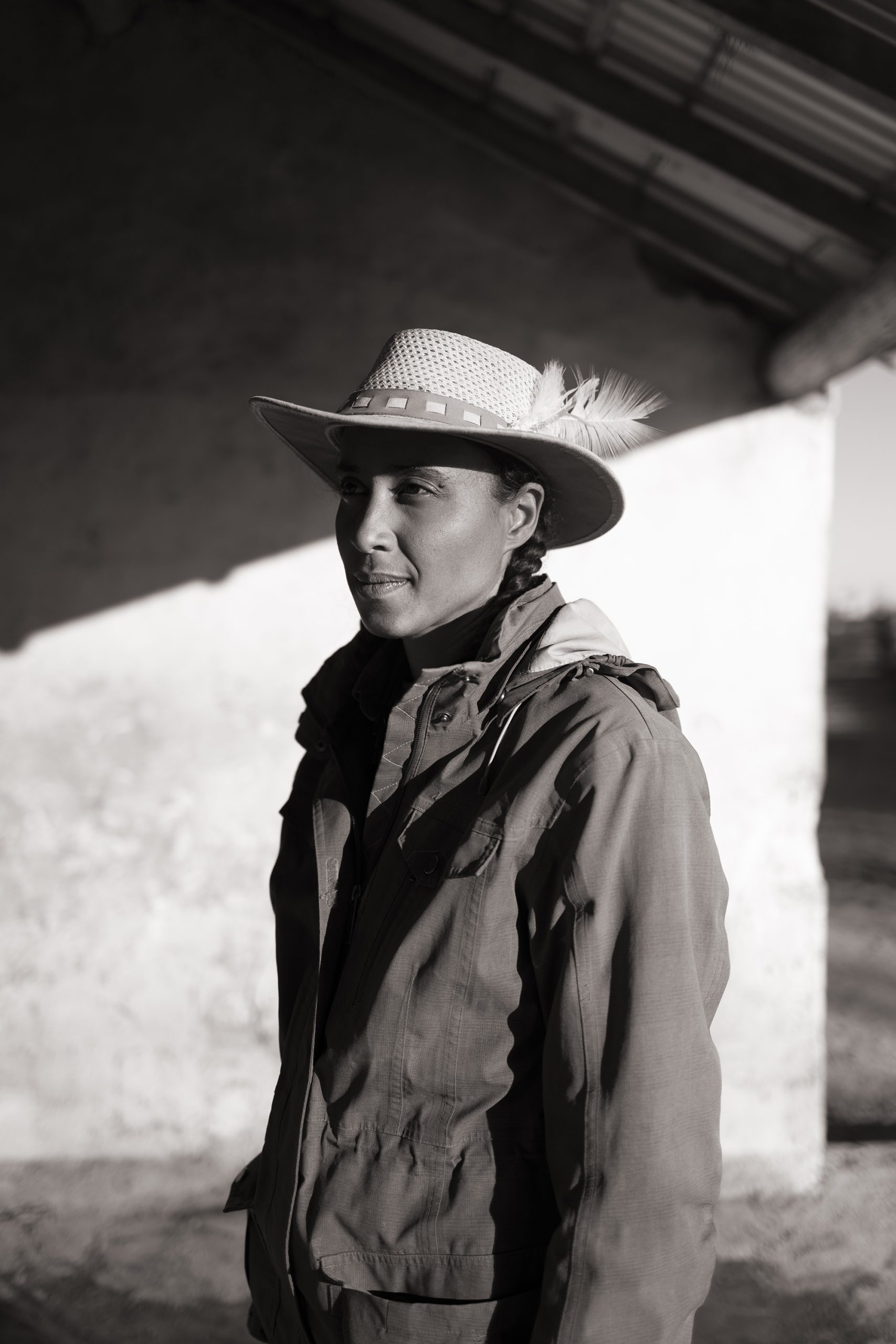 une jeune femme camarguaise regarde sur la gauche elle porte un chapeau avec une plume photographie en noir et blanc