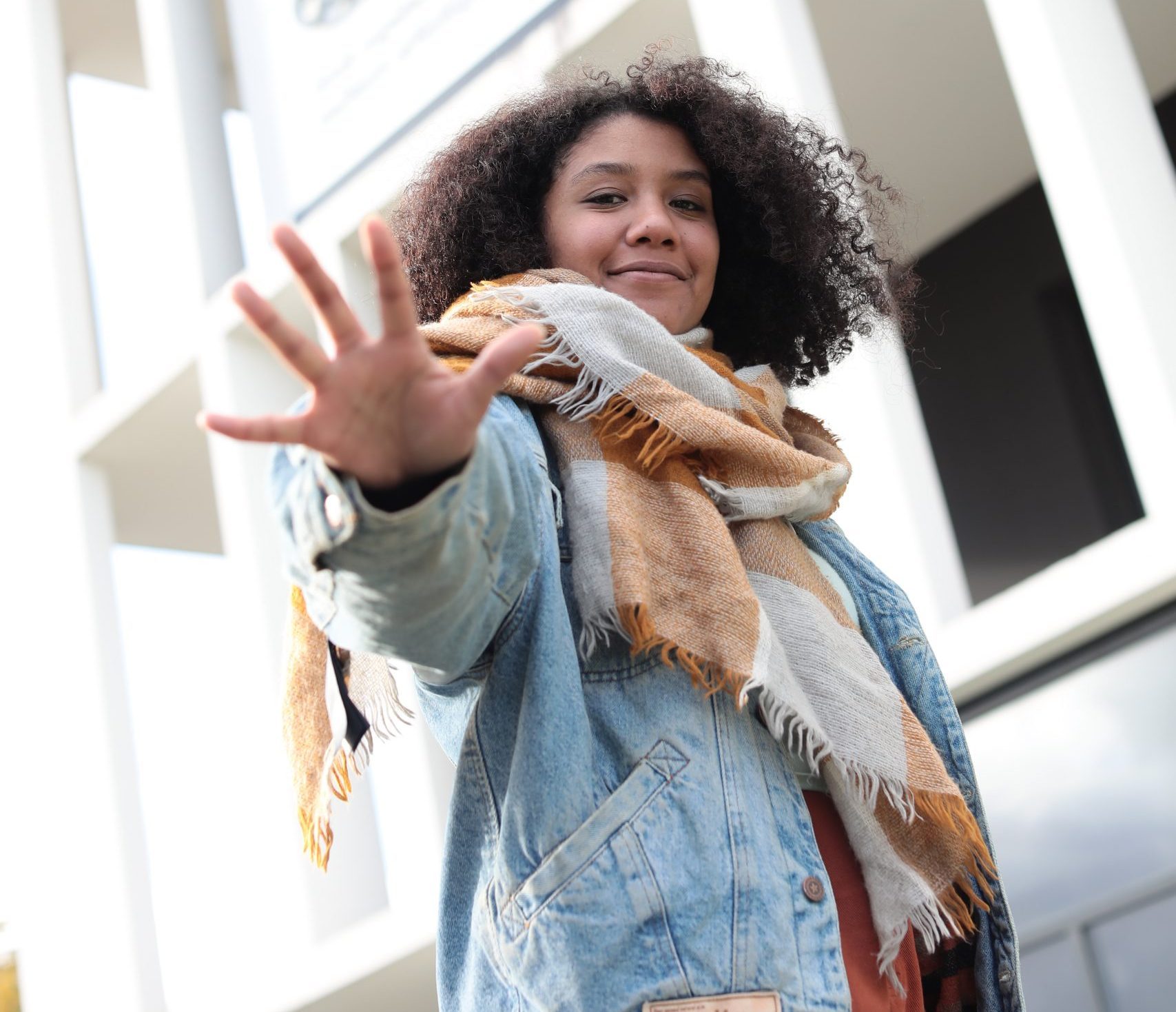 Une étudiante avec une écharpe pose devant le logo de l'ETPA devant l'entrée du campus