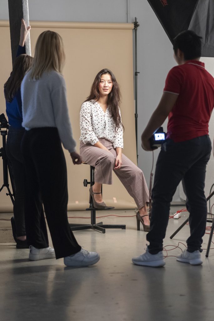 Backstage atelier mode ETPA une élève assise sur un tabouret devant l'objectif d'un camarade de l'ETPA