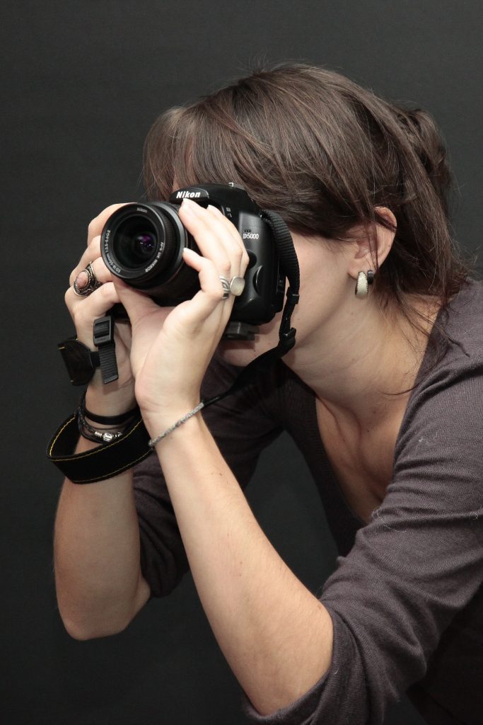 une jeune femme est concentrée en prenant une photo avec un appareil nikon dans le studio de l'ETPA